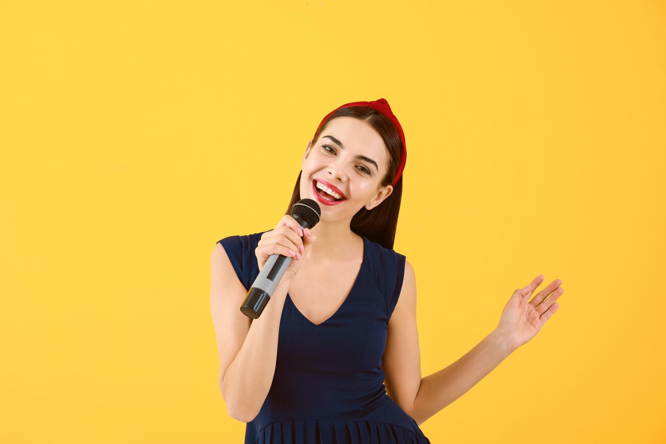 Beautiful Young Female Singer with Microphone on Color Background